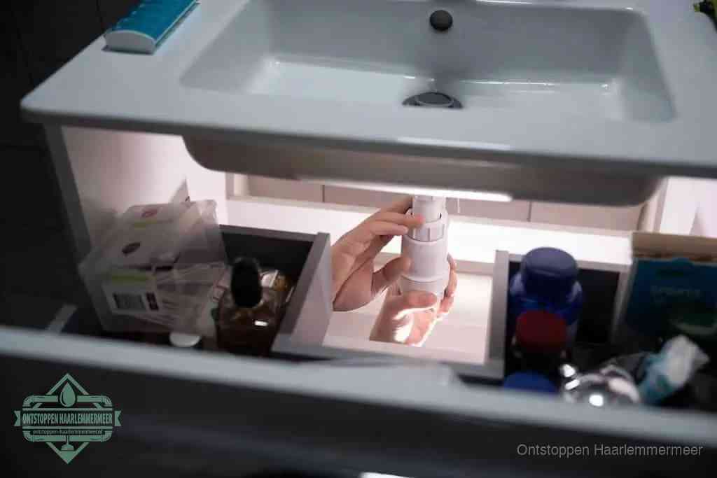 Een pompfles met zeep boven een wastafel, de heet water en afwasmiddel-methode om een vetprop in de afvoer los te maken in Haarlemmermeer