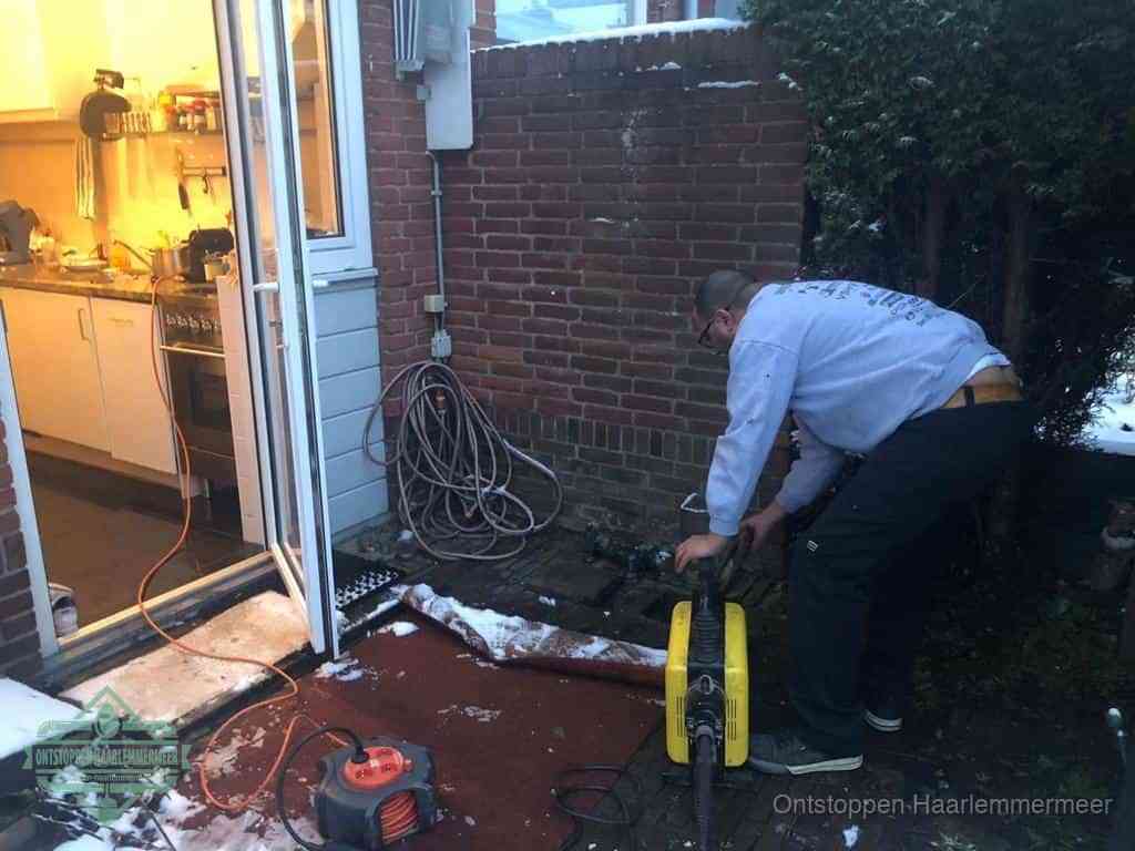 Een monteur werkt buiten bij een open riool-/grondput met een elektrische ontstoppingsmachine om een verborgen afvoerprobleem op te sporen in Haarlemmermeer