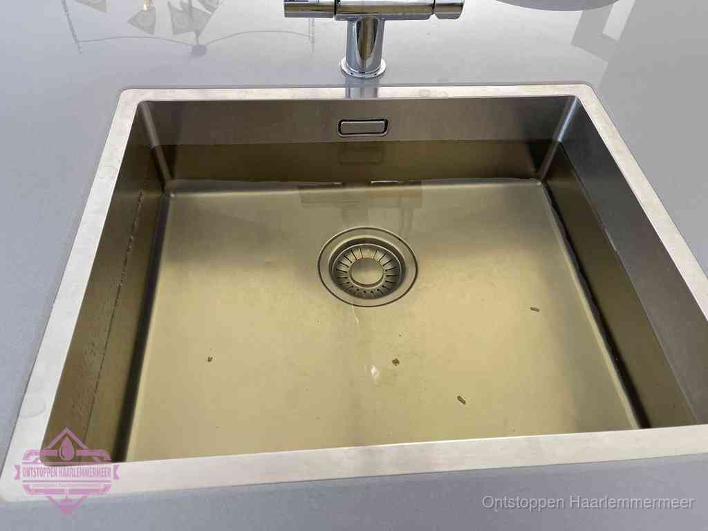 Stilstaand water in een rvs spoelbak dat niet wegloopt, een duidelijk signaal van een gootsteenverstopping in Haarlemmermeer