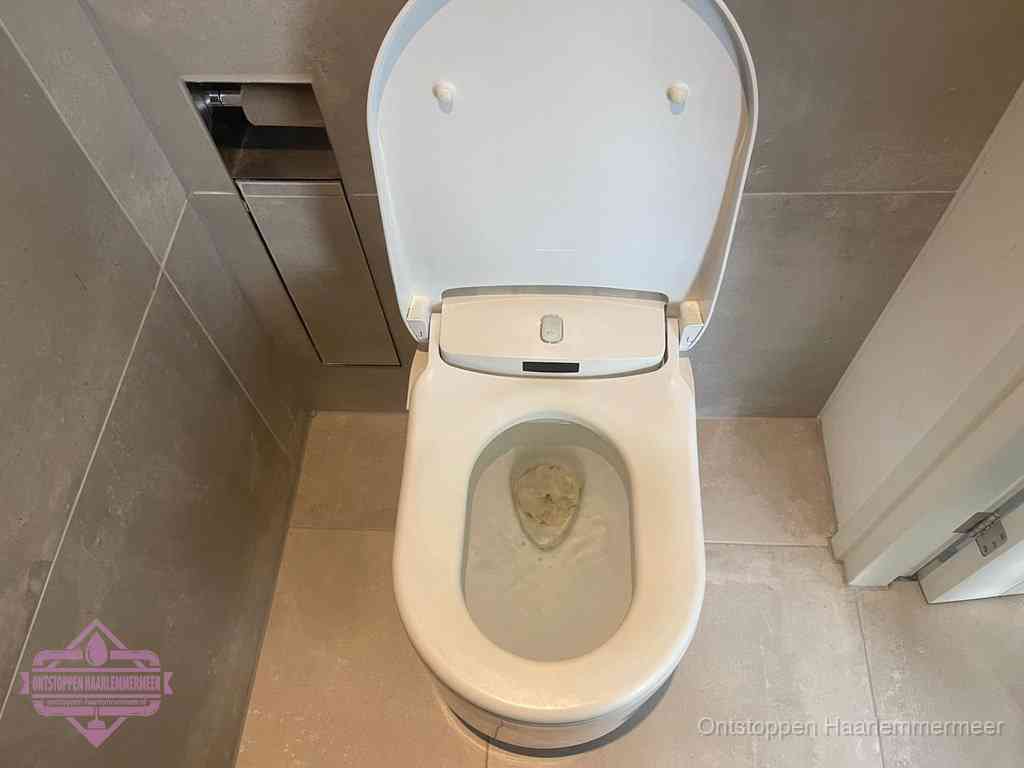 Een wit hangtoilet waarin een prop wc-papier op het water blijft drijven, een duidelijk signaal van een verstopte wc in Haarlemmermeer