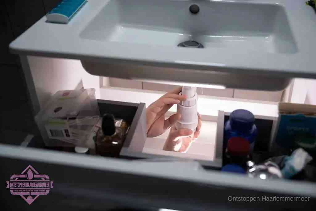 Een pompfles met zeep boven een wastafel in de toiletruimte, de warm water en afwasmiddel-methode om de wc te ontstoppen in Haarlemmermeer