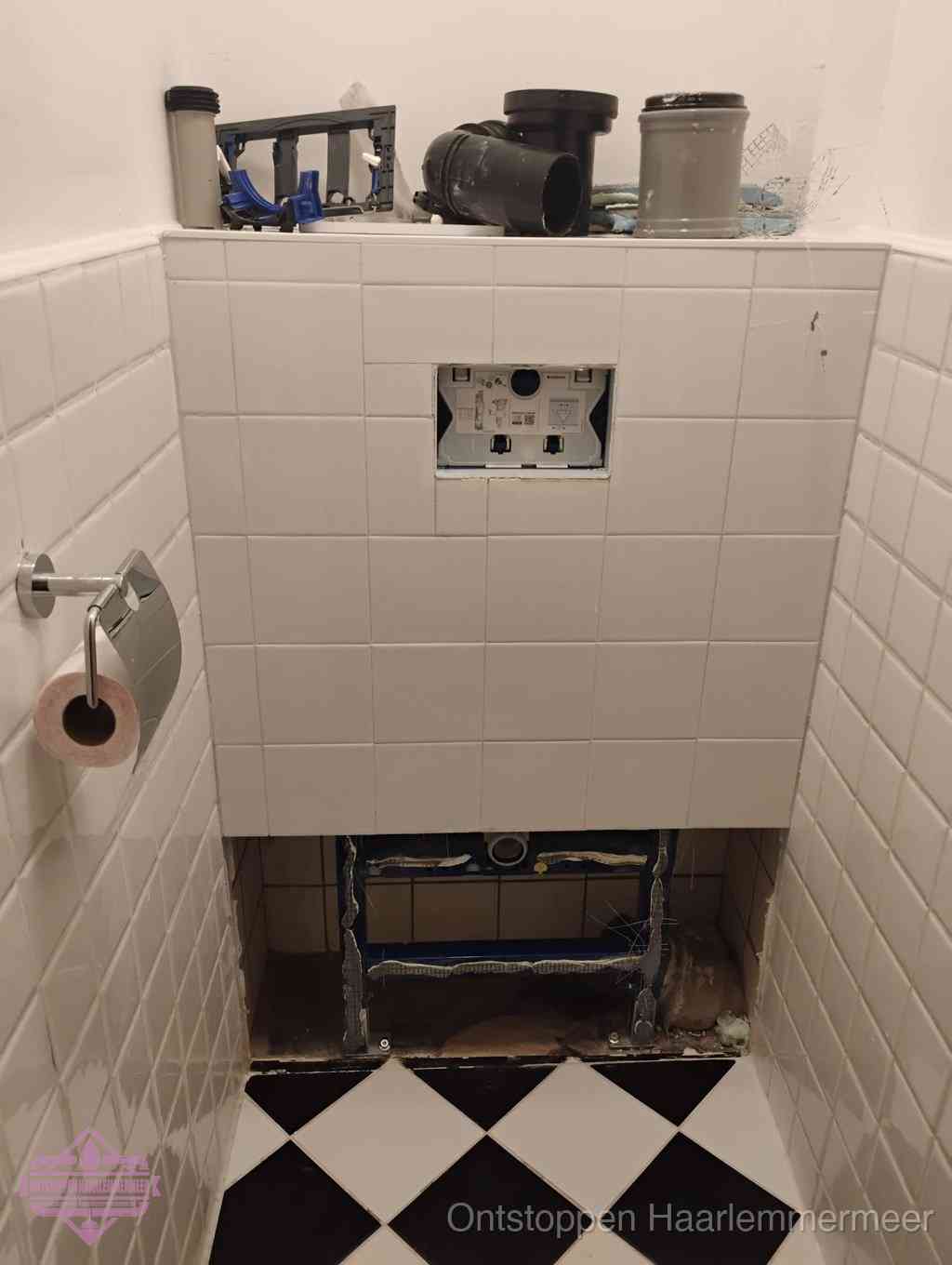 Een toiletruimte waar het hangtoilet en de inbouwreservoir-onderdelen zijn vrijgelegd voor onderhoud, periodiek nazicht voorkomt een wc-verstopping in Haarlemmermeer