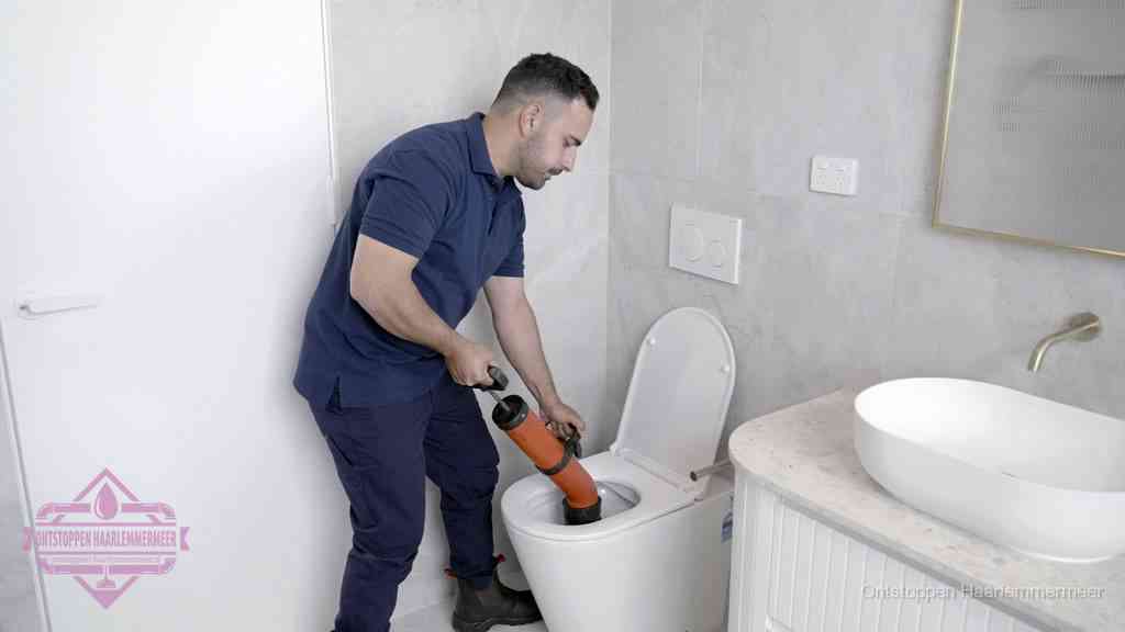 Een monteur gebruikt een handmatige perspomp (toiletontstopper) op een wandcloset tijdens het professioneel wc ontstoppen in Haarlemmermeer